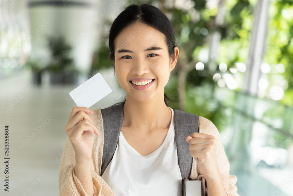Happy smiling Asian female student holding blank credit card, concept of student card, student loan, scholarship money, educational financial credit Happy smiling Asian female student holding blank credit card, concept of student card, student loan, scholarship money, educational financial credit