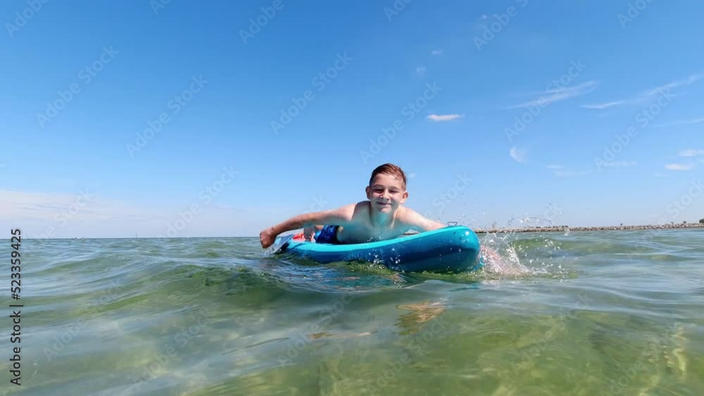 Handsome teen boy swiming on sup board in sea at summer vacation Handsome teen boy swiming on sup board in sea at summer vacation