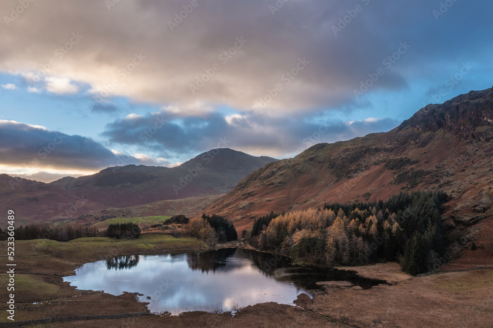 Beautiful aerial drone landscape image of sunrise from Blea Tarn in Lake District during stunning Autumn showing