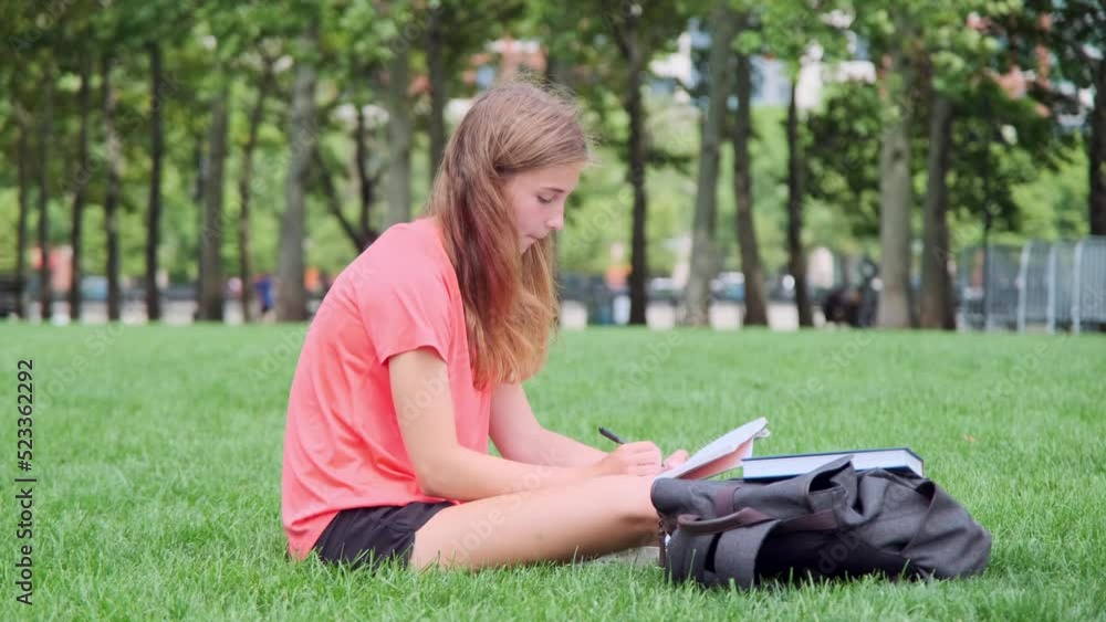 Girl in orange shirt Reading Book on the grass in Summer Girl in orange shirt Reading Book on the grass in Summer