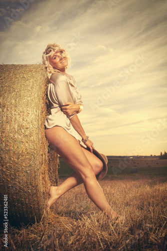 Fototapeta Pretty lady in summer apparel posing on harvested cornfield