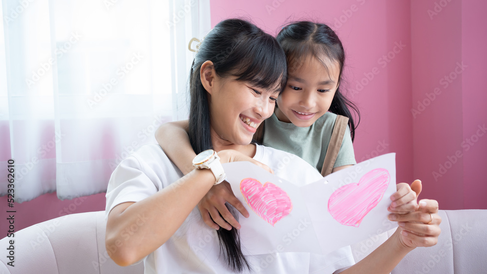 Happy mother's day.Asian Child daughter congratulates mom and gives her postcard. Mum and girl smiling and hugging. Family holiday and togetherness. Happy mother's day.Asian Child daughter congratulates mom and gives her postcard. Mum and girl smiling and hugging. Family holiday and togetherness.