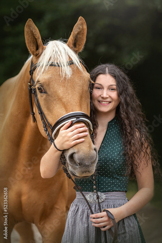 Equestrian and her horse team: Portrait of a young woman cuddle with her palomino kinsky warmblood horse. 