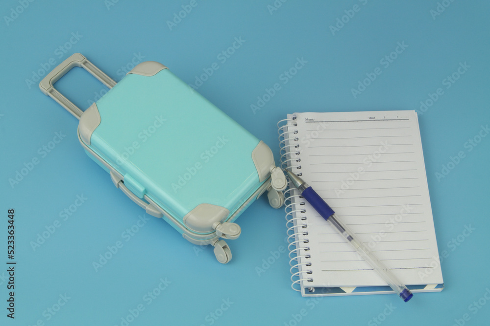 Travel suitcase with notebook and pen. Planning travel trip and vacation concept. Travel suitcase with notebook and pen. Planning travel trip and vacation concept.