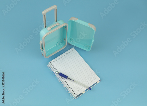 Open travel suitcase with notebook and pen. Planning travel concept.