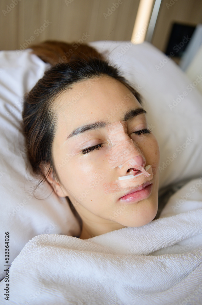 Asian woman with bandage on her nose after rhinoplasty Asian woman with bandage on her nose after rhinoplasty
