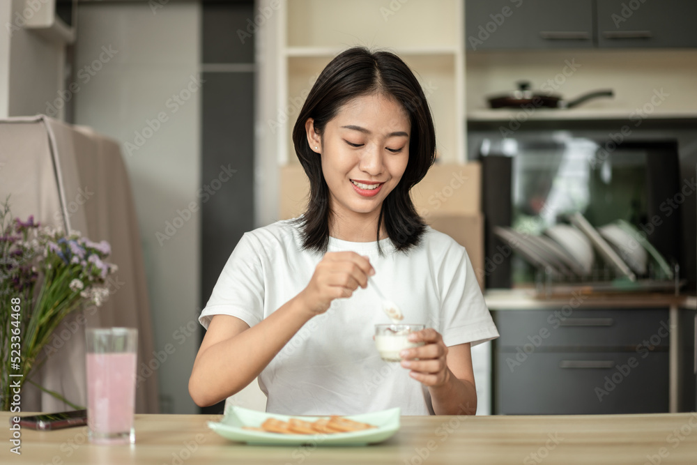 Tanned Asian woman eating yogurt and crackers for breakfast, Health care by eating a diet that is low in fat and calories, The most popular food of the working age, Wake-up activities Tanned Asian woman eating yogurt and crackers for breakfast, Health care by eating a diet that is low in fat and calories, The most popular food of the working age, Wake-up activities