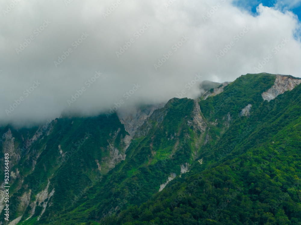 Green slopes and rugged cliffs near peak of Mt. Daisen in Tottori, Japan