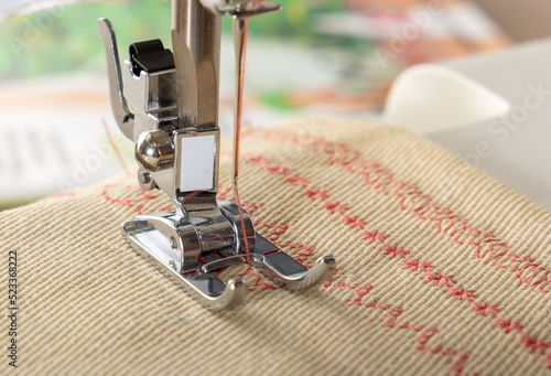 Sewing machine foot with a needle sews fabric. Close-up. Place for text