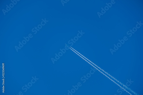 Airplane contrail against clear blue sky background with copyspace.