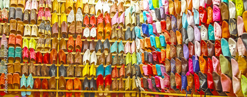 Store shelf with choice of many colorful typical oriental moroccan babouches leather slippers - Morocco