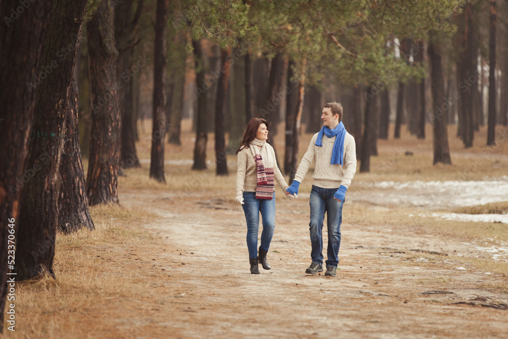 couple on a date walk in autumn or winter park. Valentine's Day for couple in rustic style. Happy couple in love. Casual outfit with Blue accessories: scarfs and mittens. Cozy winter in Pine forest couple on a date walk in autumn or winter park. Valentine's Day for couple in rustic style. Happy couple in love. Casual outfit with Blue accessories: scarfs and mittens. Cozy winter in Pine forest