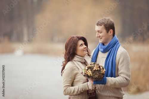 couple on a date walk in autumn or winter park. Valentine s Day for couple in rustic style. Happy couple in love. Casual outfit with Blue accessories  scarfs and mittens. Cozy winter in Pine forest