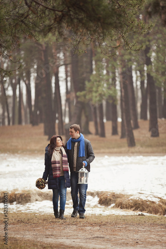couple on a date walk in autumn or winter park. Valentine's Day for couple in rustic style. Happy couple in love. Casual outfit with Blue accessories: scarfs and mittens. Cozy winter in Pine forest