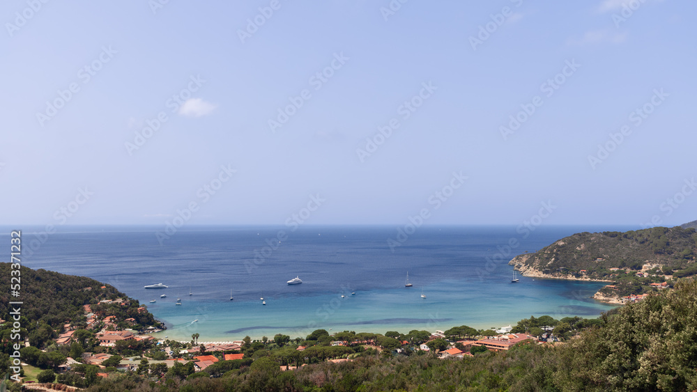 Typical bay of the North coast of Elba island with low hills covered with dense forest, emerald water in small cozy bays, and white sandy beaches, Province of Livorno, Italy