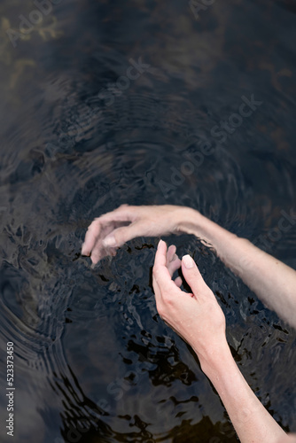 woman s hand gently touches the water in the pond  a close horizontal photo on the theme of tranquility