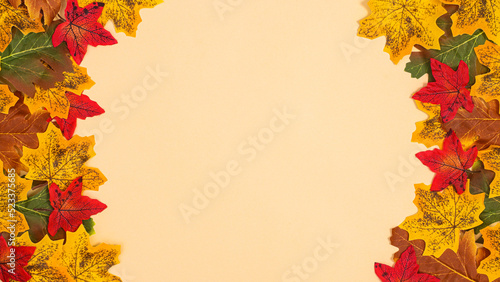 Autumn colorful leaves on left and right side of beige background with copy space. Flat lay