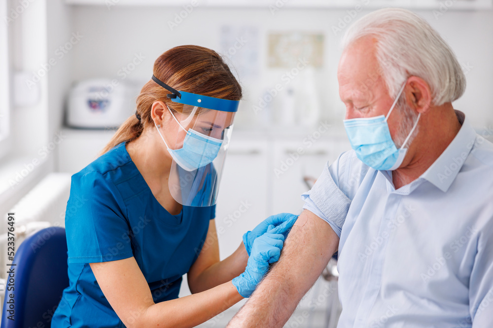 Nurse disinfecting senior patient vaccine application spot Nurse disinfecting senior patient vaccine application spot