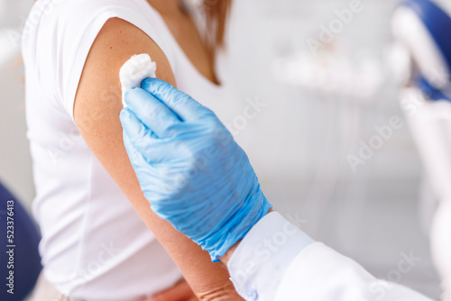 General practitioner disinfecting patient vaccine application spot