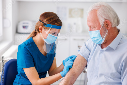 Nurse disinfecting senior patient vaccine application spot