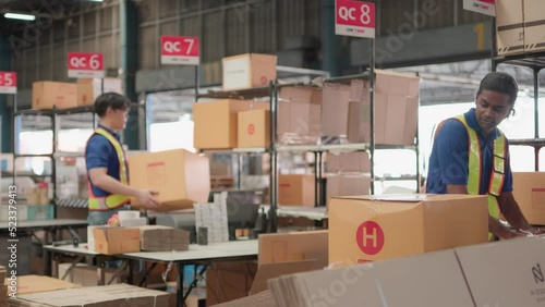 Two asian warehouse worker working checking package products in warehouse, logistic. While staff used laser barcode scanner on cardboard box, distribution center, placement in storage for shipping.