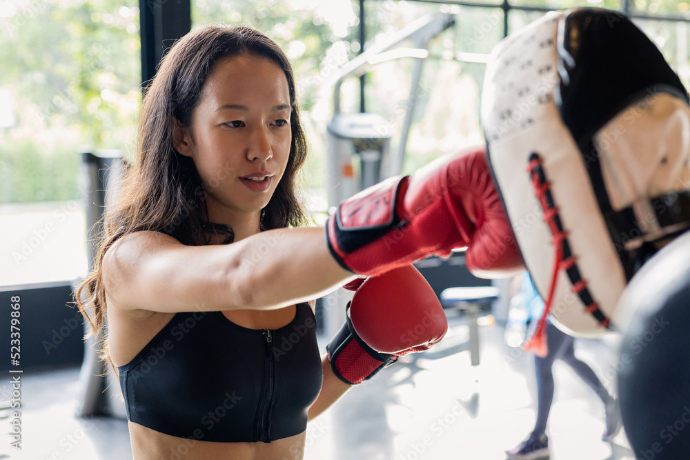 Young woman doing boxing training with her coach.