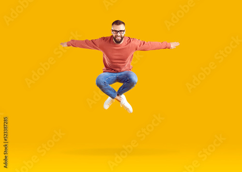 Excited energetic young Caucasian man millennial jumping high with arms outstretched celebrating success or feeling joy after winning jackpot lottery posing in orange studio. Happiness from triumph © Studio Romantic