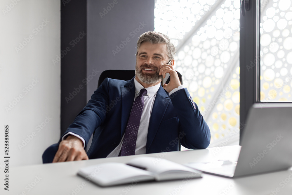 Phone Call. Smiling Mature Businessman In Suit Talking On Cellphone At Workplace Phone Call. Smiling Mature Businessman In Suit Talking On Cellphone At Workplace