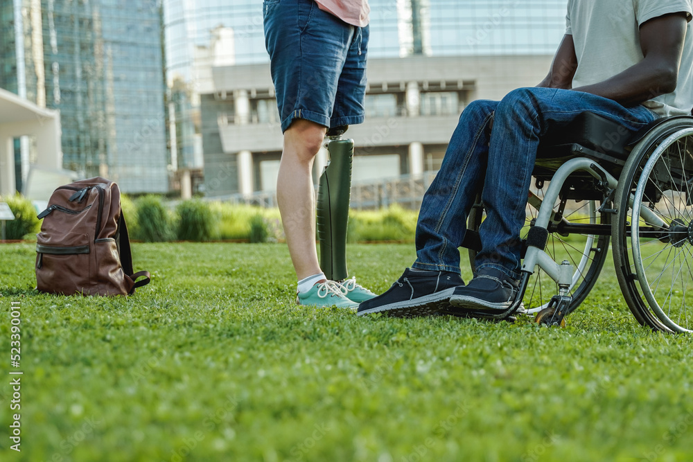 Obraz premium Diverse friends with physical disability having fun outdoor at city park - Focus on African man on wheelchair