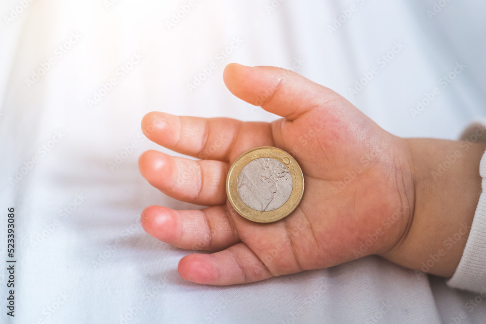 Inflation and financial security concept: Close up of newborn baby holding a euro coin Inflation and financial security concept: Close up of newborn baby holding a euro coin