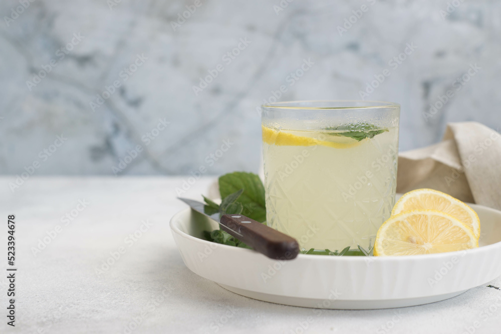 Fototapeta premium A glass of lemonade with lemon on a gray background.