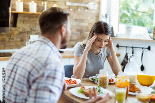 Wallpaper Mural Young woman having a headache while arguing with her boyfriend during breakfast time at home Torontodigital.ca