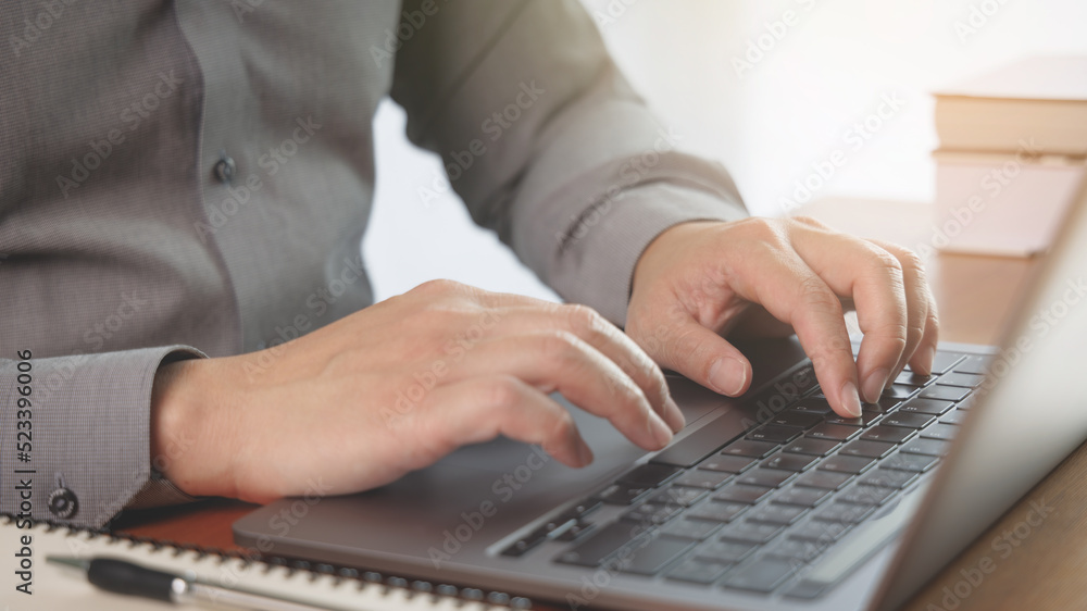 businessman using laptop and his hand is typing on keyboard while working or browsing Internet in modern business office workspace. Computer network and mobile office concept. businessman using laptop and his hand is typing on keyboard while working or browsing Internet in modern business office workspace. Computer network and mobile office concept.
