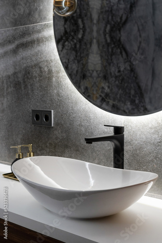 Foto white washbasin, modern black faucet and mirror in washroom