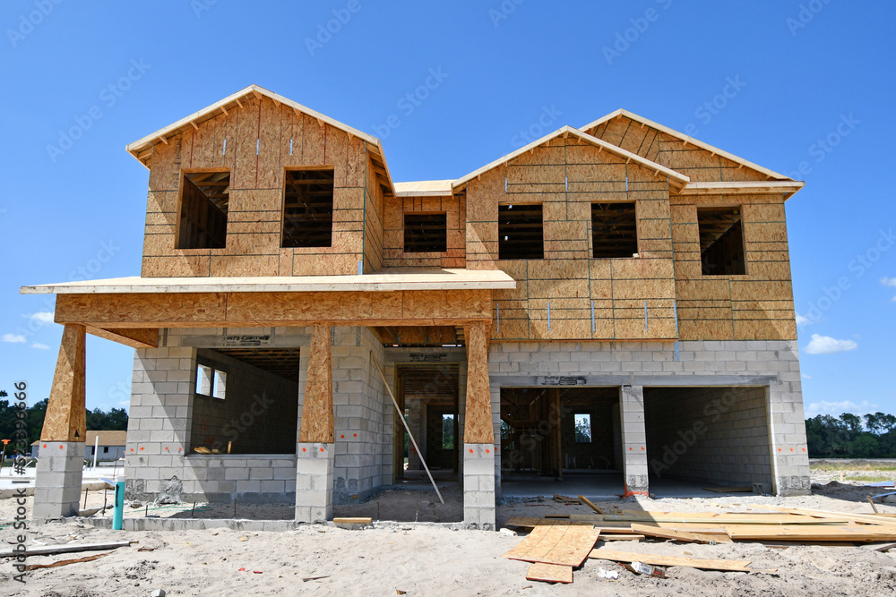 Incomplete new two story residential home under construction at wood frame under blue skies in central Florida Incomplete new two story residential home under construction at wood frame under blue skies in central Florida