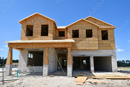 Incomplete new two story residential home under construction at wood frame under blue skies in central Florida