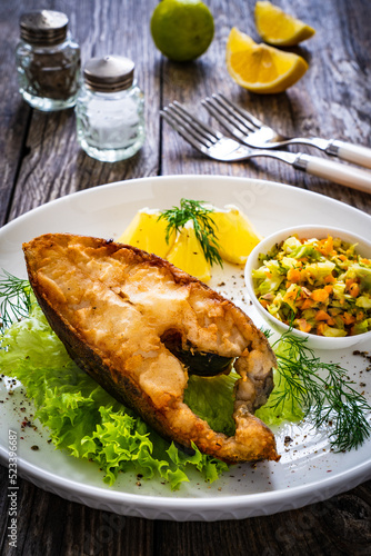 Schilderij op canvas Fish dish - fried halibut with French fries and lemon on wooden table