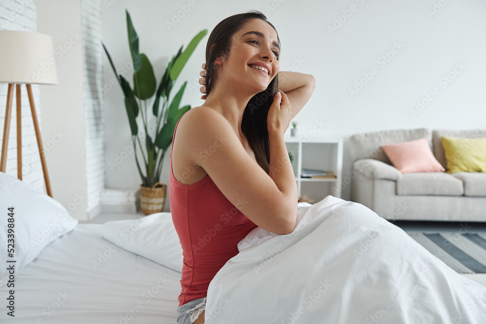 Happy young woman enjoying lazy time in bed after waking up Happy young woman enjoying lazy time in bed after waking up