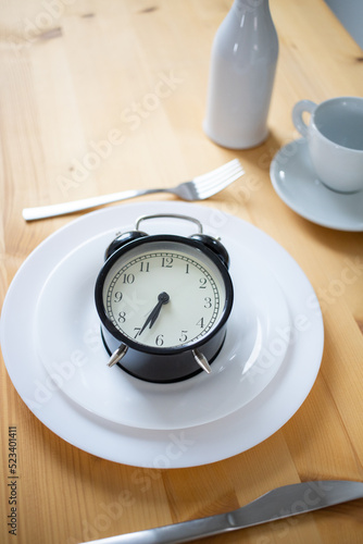 intermittent fasting concept alarm clock on kitchen table