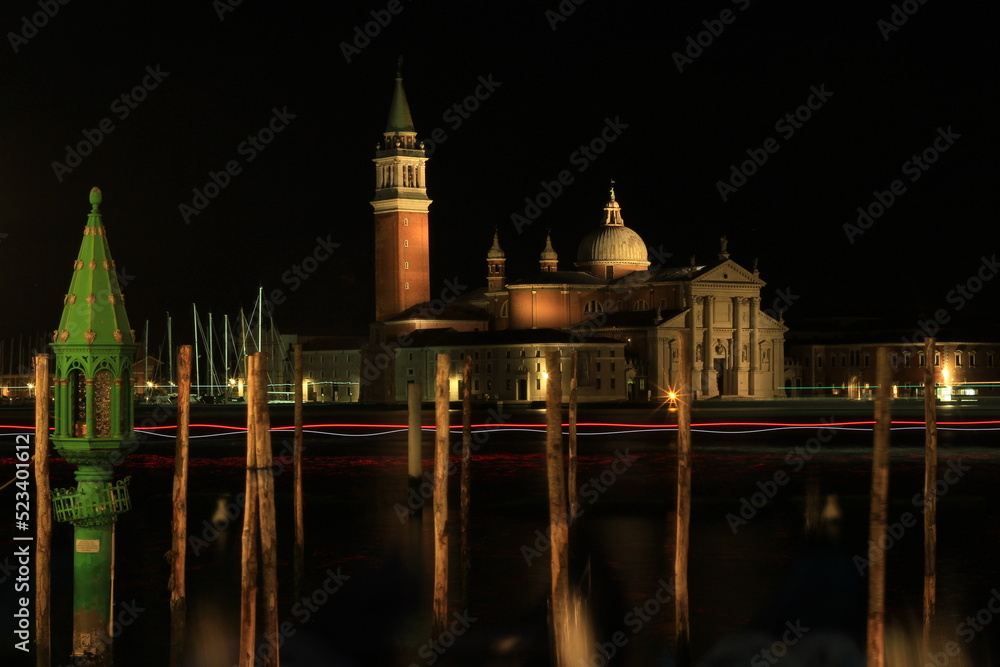 Venice by night, beautiful night view of the island of San Giorgio Maggiore, in the foreground the Grand Canal and gondolas, vacation / tourism in Italy, city landscape at night.