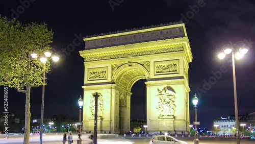 The Arc de Triomphe night timelapse hyperlapse. Famous monument in Paris, standing at the western end of the Champs-Elyseees. Traffic on circle road. photo