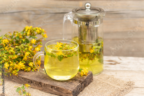 St. John's wort tea is a therapeutic healthy drink A teapot and a cup on a wooden background A bouquet of St. John's wort on the table The concept of medicinal herbs, phytotherapy