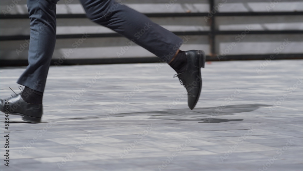 Businessman legs running city street in black shoes closeup. Morning commute Businessman legs running city street in black shoes closeup. Morning commute