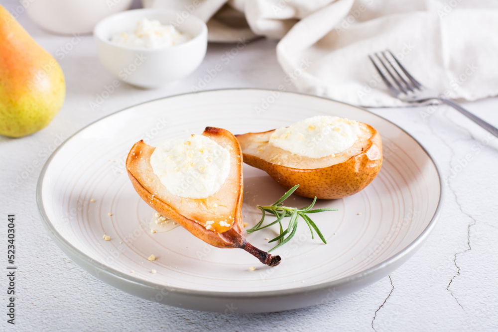 Baked pears with ricotta, nuts, honey and rosemary on a plate on the table. Homemade dessert. Baked pears with ricotta, nuts, honey and rosemary on a plate on the table. Homemade dessert.