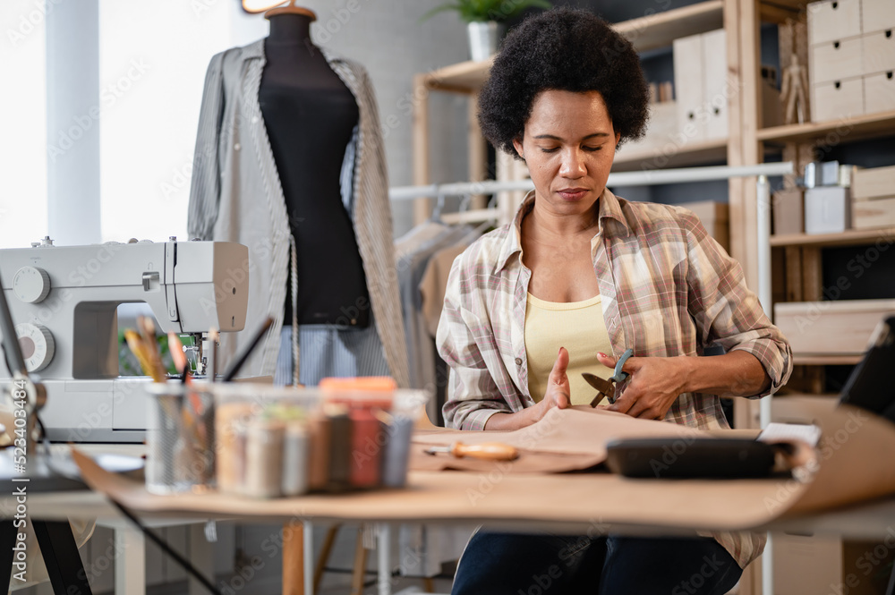 Fototapeta premium Young black entrepreneur women working in her workshop. Woman tailor.