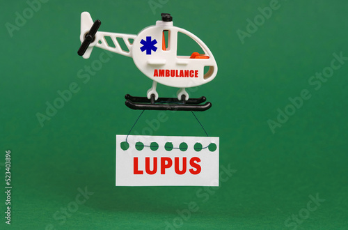 On a green surface, an ambulance helicopter with a sign - LUPUS