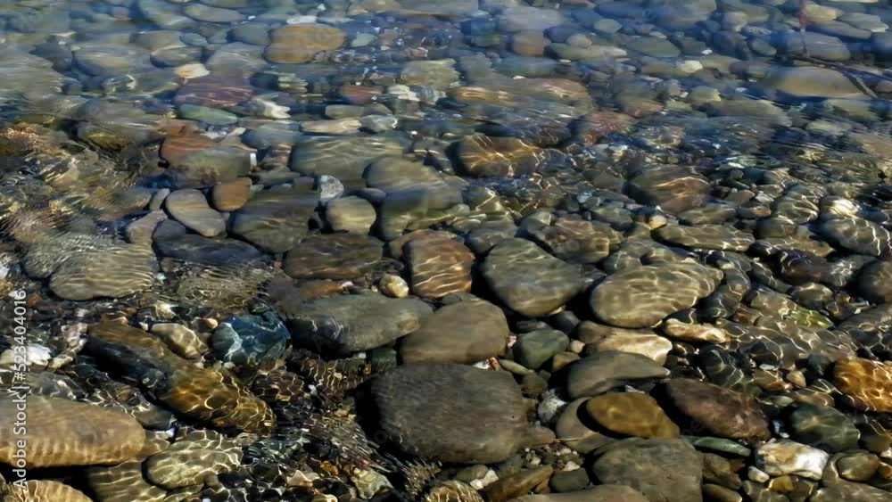 Slow motion flow of water of a mountain river with stones under water. Flow of water in shallow water. Relaxing and peaceful slow stream of water with pebbles under water surface. Beautiful nature. Slow motion flow of water of a mountain river with stones under water. Flow of water in shallow water. Relaxing and peaceful slow stream of water with pebbles under water surface. Beautiful nature.