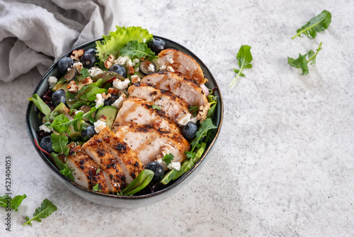 Fotografía Grilled chicken breast, fillet and fresh vegetable salad of lettuce, arugula, spinach, avocado, onion and pecan nut with blueberry