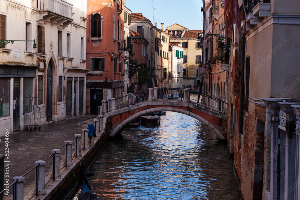 The old bridge made with red bricks on the typical canal in Venice