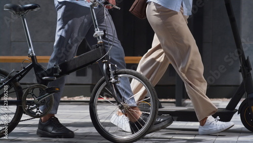 Workers legs walking downtown with electric scooter bicycle in hands close up. photo